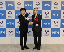 大阪大学総長・西尾章治郎様(右)と握手を交わすNTN代表取締役社長・大久保博司(左)