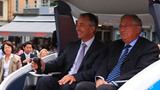 「Q'mo（キューモ）」に乗車するJean Luc RIGAUT （リゴー）、アヌシー市長（左）とDidier SEPULCHRE（セピュルクル）、NTN-SNR会長（右）